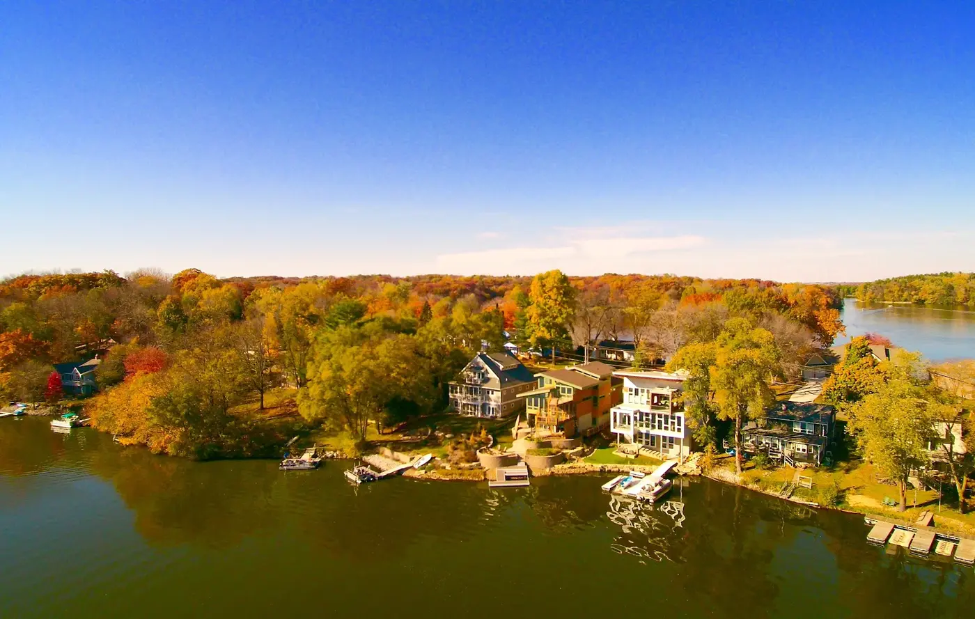 Aerial drone view of lake property surrounded by fall-color trees