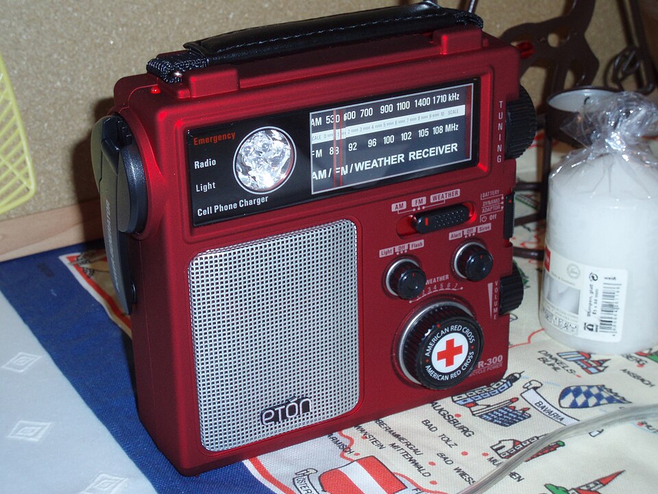 A red Eton emergency radio with a tuning dial, speaker grille and hand crank