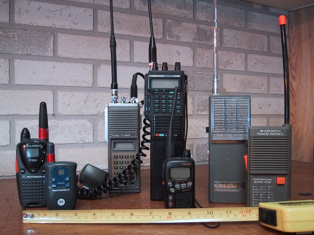 Several handheld walkie-talkies of different makes standing side by side